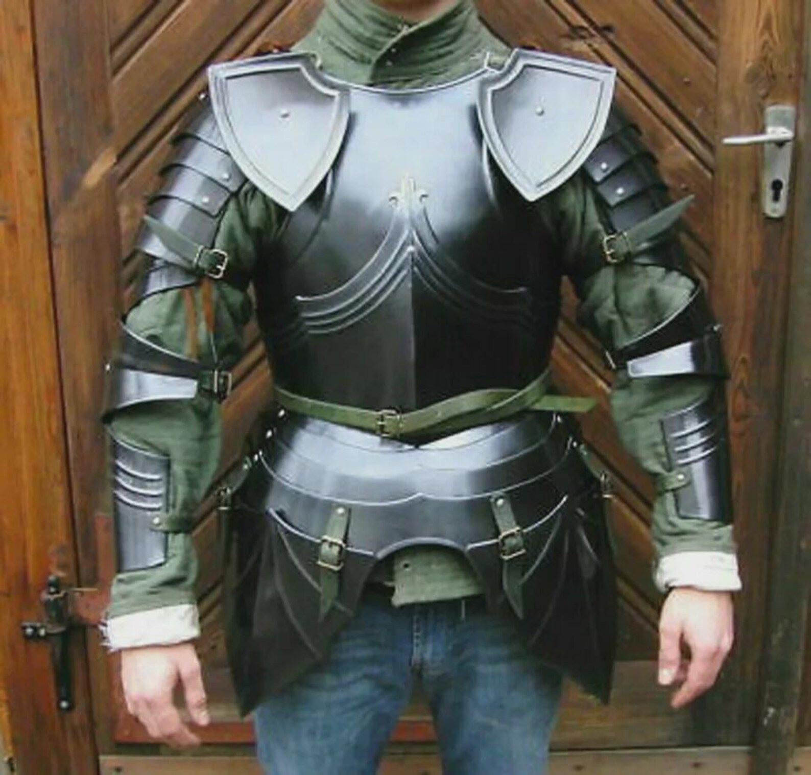 Person wearing a medieval steel armor suit with chest plate, shoulder guards, and arm protection.