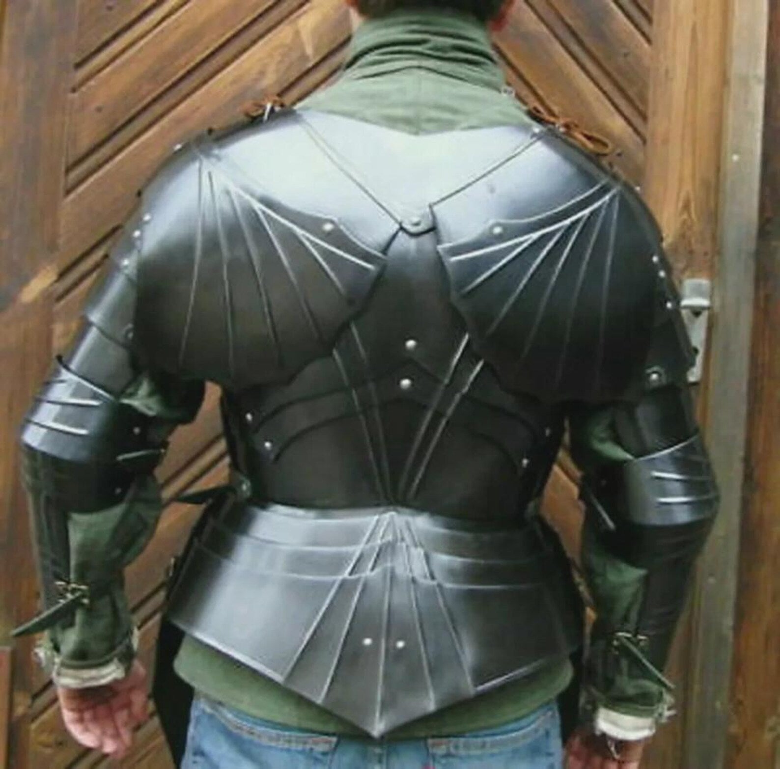 Person wearing a black medieval steel armor suit with chest plate, shoulder guards, and arm protection.