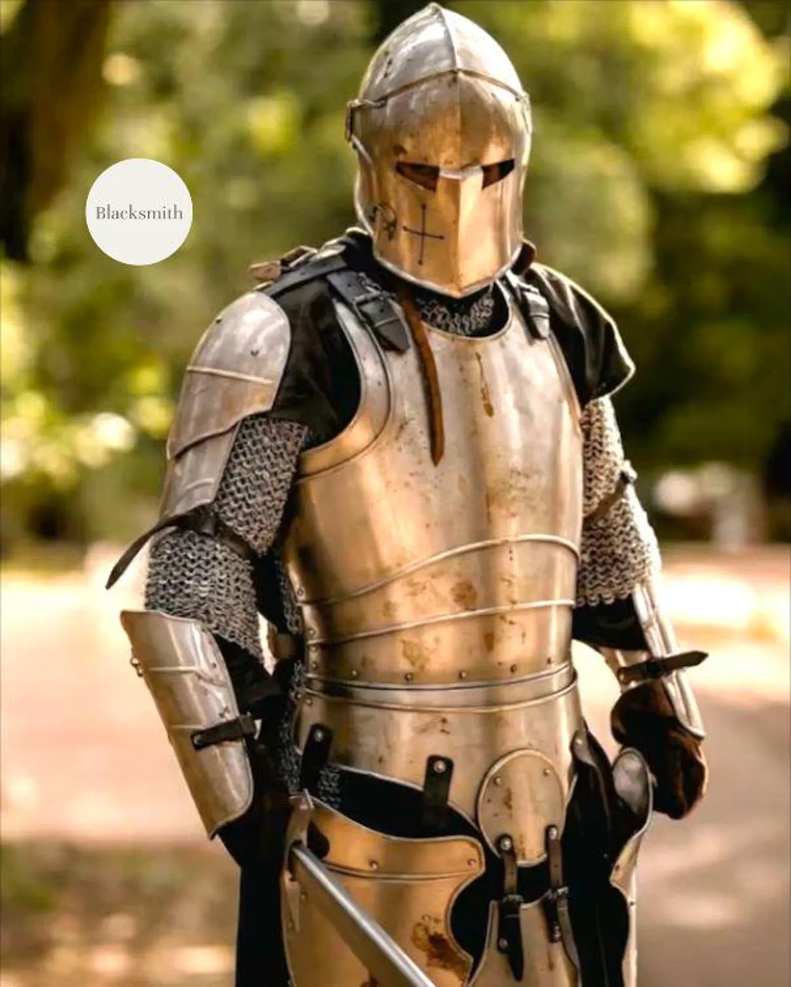 Person wearing a full medieval steel knight armor suit with helmet, holding a sword.