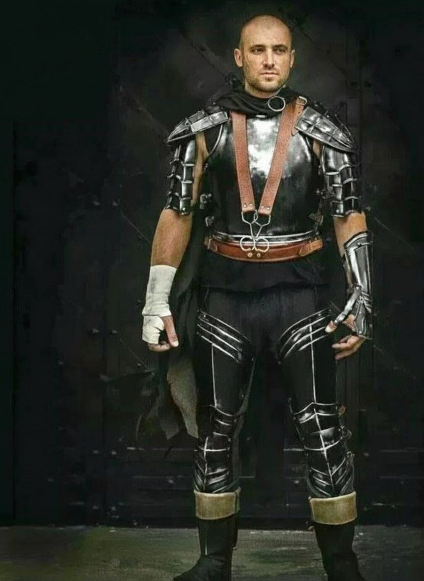 Person wearing a black medieval warrior armor set with steel shoulder plates, leather chest harness, and armored leg guards.