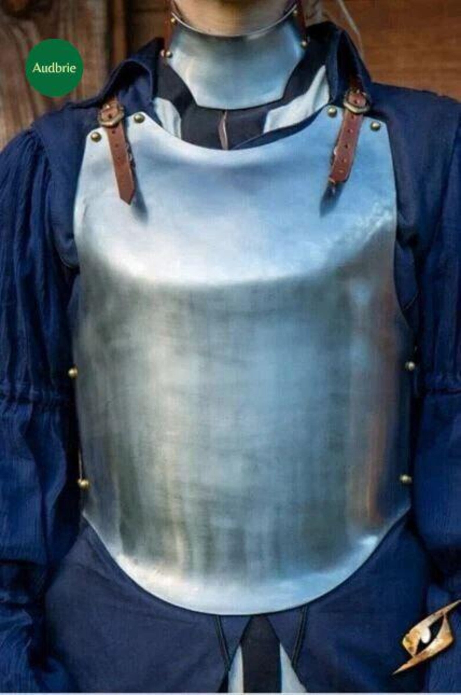 Person wearing a metal breastplate with a blue garment underneath, brand 'Audrie' visible.