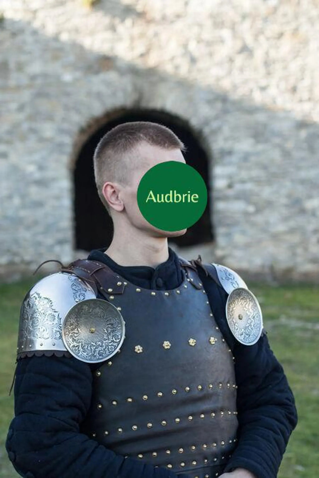 Person wearing medieval armor with a blurred face and 'Audbrie' logo.